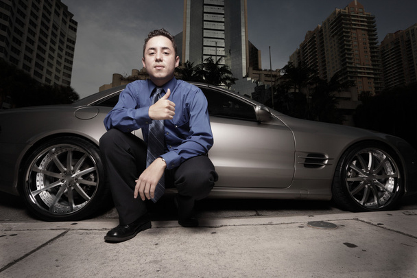 Empresario posando en un coche deportivo de lujo y haciendo gestos con un pulgar hacia arriba
 - Foto, imagen