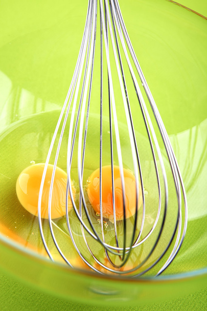 Ручной миксер с яйцами в стеклянной чаше на зеленом фоне
 - Фото, изображение