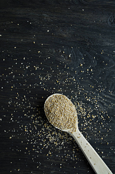 Wheat groats in a wooden spoon on a wooden dark background. Wooden spoon with wheat grains. - Foto, Bild