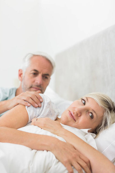 Woman ignoring mature man while lying in bed at the home - Φωτογραφία, εικόνα