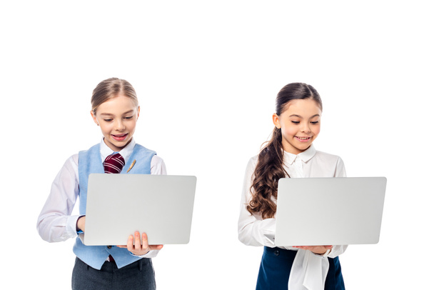 smiling schoolgirls in formal wear using laptops Isolated On White - Foto, imagen