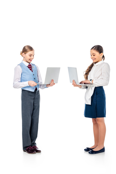 smiling schoolgirls in formal wear using laptops On White - Foto, Bild