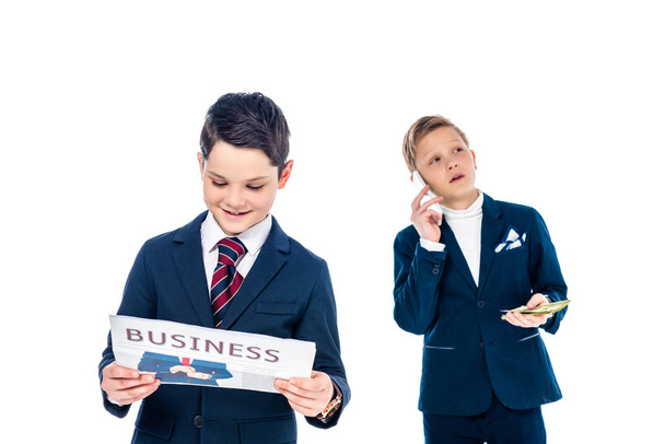 schoolboy with money talking on smartphone while other boy reading newspaper pretending to be businessmen Isolated On White  - Foto, Imagen