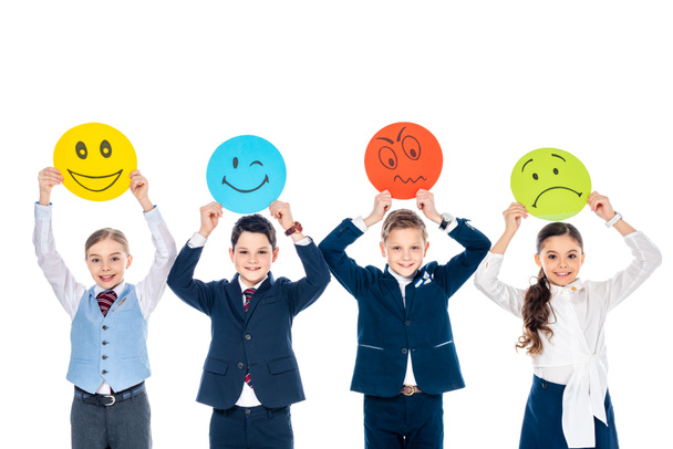 niños felices en ropa formal sosteniendo tarjetas con varias expresiones faciales aisladas en blanco
 - Foto, Imagen