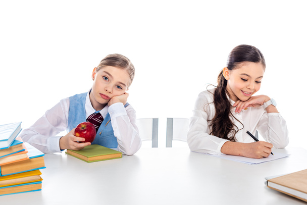 schoolgirls in formal wear sitting at desk with books and writing Isolated On White - Photo, Image