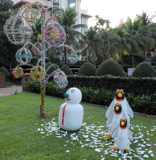 hóember és három pingvinek a zöld gyep, kerti szobor, pálmafák és díszítő fák - Fotó, kép