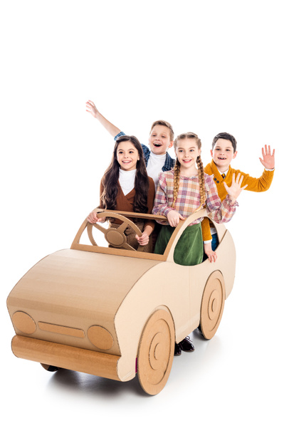 happy kids sitting in cardboard car, waving and cheering on white - Photo, Image