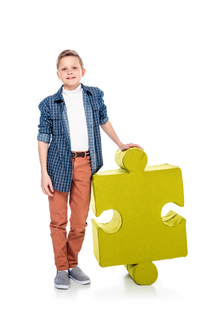 happy boy with jigsaw puzzle piece looking at camera on white - Photo, Image