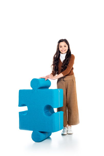 smiling kid with jigsaw puzzle piece looking at camera on white - Photo, image