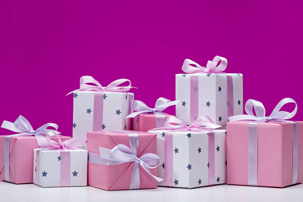 Boxes with gifts on pink background. Stylish modern gifts in white paper with asterisks, decorated with pink satin ribbon with bows. Holiday concept, copy space. - Fotografie, Obrázek