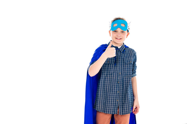 glücklicher Junge im Superheldenkostüm zeigt Daumen hoch Zeichen isoliert auf weiß mit Kopierraum - Foto, Bild