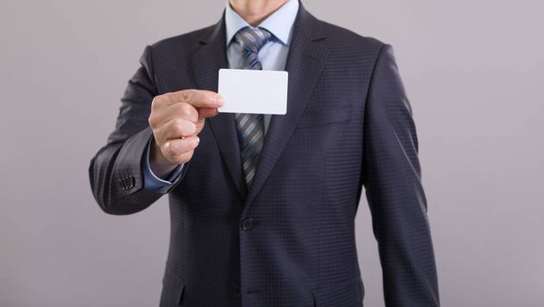 Main d'un homme d'affaires avec une carte blanche sur fond gris
. - Photo, image