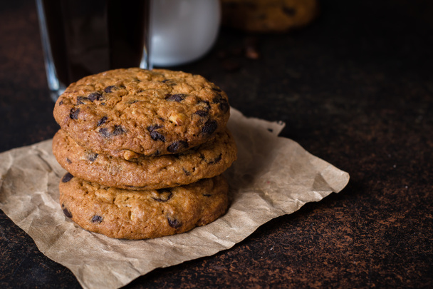 Kávé üveg és tej csokoládé chip cookie a sötét kőből betonasztal háttérben. Reggel reggeli koncepció. Lemezterület másolása - Fotó, kép