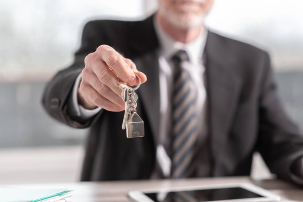 Агент по недвижимости предлагает ключи от дома
 - Фото, изображение