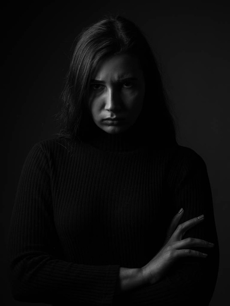 Portrait of a displeased young woman. Black and white. Low key - Photo, Image