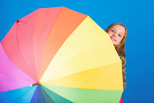 Kid peek out colorful rainbow umbrella. Color your life. Girl cheerful hide behind umbrella. Colorful umbrella accessory. Weather forecast concept. Stay positive though rainy day. Brighten up life - Zdjęcie, obraz