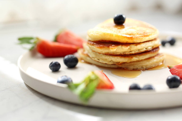 Homemade pancakes with strawberries, blueberries and maple syrup. Sweet breakfast. - Photo, Image