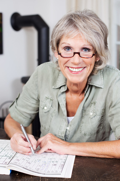 Smiling elderly woman doing a crossword puzzle - Foto, Bild