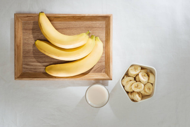 Bananes et morceaux de bananes dans une assiette en bois
 - Photo, image