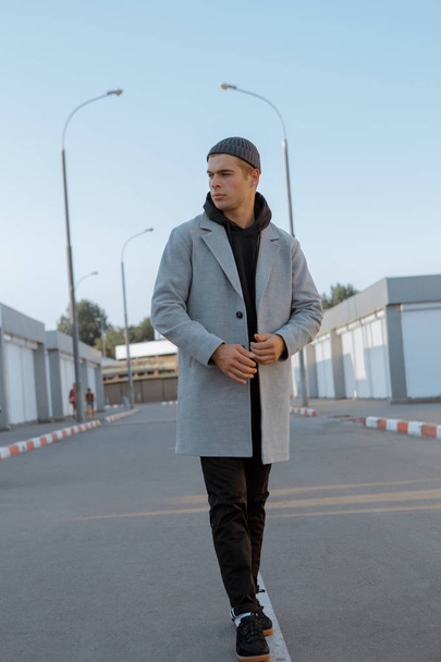 Handsome guy in stylish clothes walks on a city street at sunset - Photo, Image