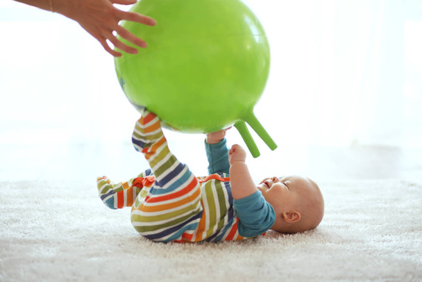 Ребенок играет с гимнастическим мячом с мамой дома - Фото, изображение