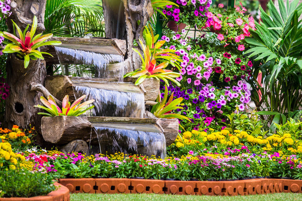 Flujos de cascada en acogedor jardín de flores caseras
 - Foto, Imagen