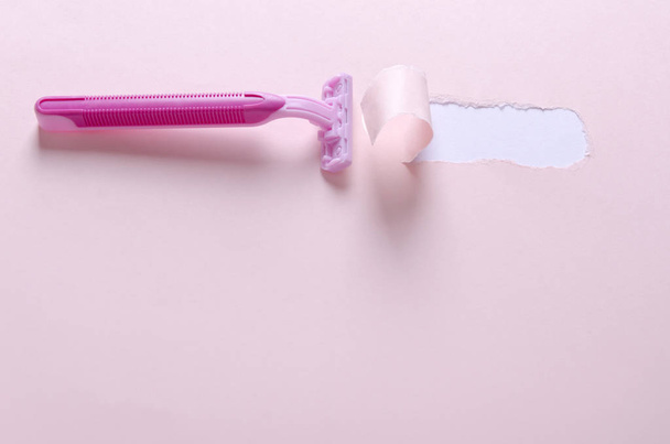 Navaja para mujer en el fondo rosa. Arpa y afeitado seguro. Papel rasgado después de usar la cuchilla
 - Foto, Imagen