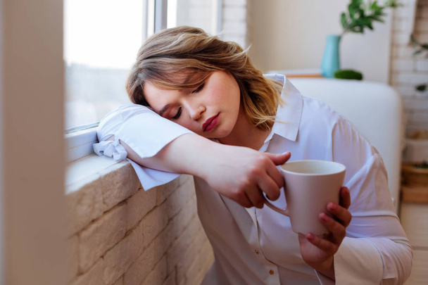 Nice tired woman falling asleep with a cup of tea - Фото, изображение