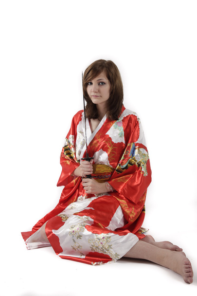 γαλλική νεαρή κοπέλα γκέισα σε κόκκινο μετάξι κιμονό με ιαπωνικό ξίφος - Φωτογραφία, εικόνα
