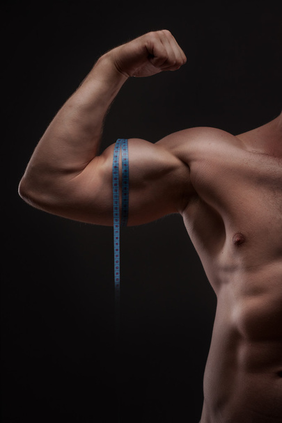 Man measures his biceps with measuring tape - Φωτογραφία, εικόνα