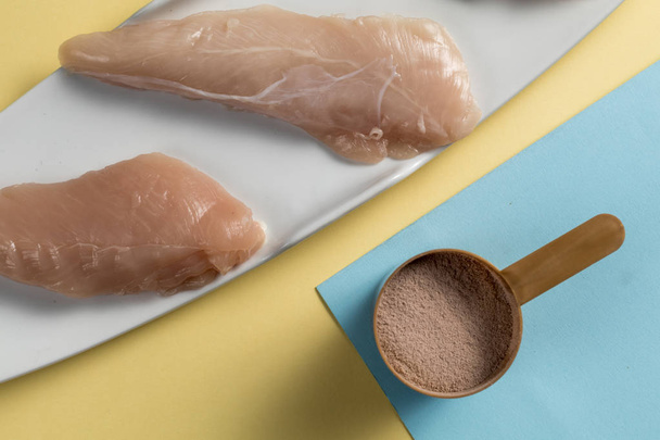 Raw chicken Breasts and a whey protein scoop cocoa flavor. Sport nutrition - Photo, Image