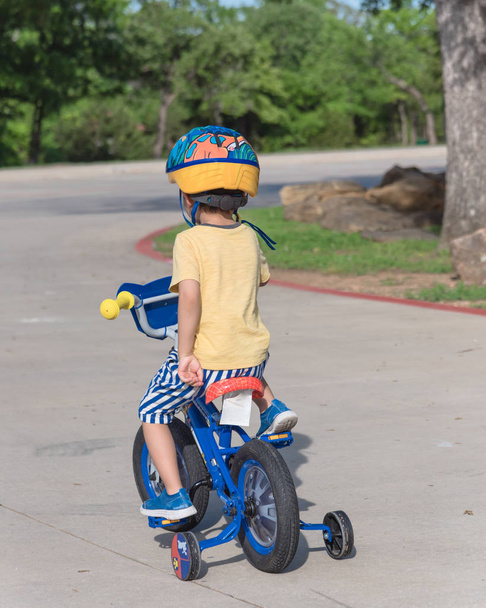 Hátsó kilátás az egészséges ázsiai gyerek lovaglás biciklit az amerikai parkban - Fotó, kép