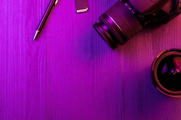 Camera, pencil, fish eye lens and SD card. Pink light. Workspace top view. Copy space. Wood background - Photo, Image