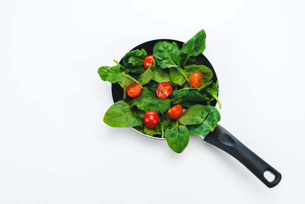 green fresh spinach leaves with cur cherry tomatoes in frying pan on white background - Photo, Image