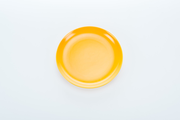 верхний вид блестящей пустой желтой пластины на белом фоне
 - Фото, изображение