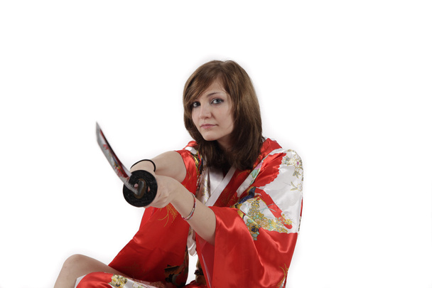 γαλλική νεαρή κοπέλα γκέισα σε κόκκινο μετάξι κιμονό με ιαπωνικό ξίφος - Φωτογραφία, εικόνα