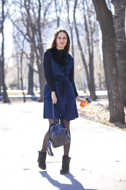 Portrait of a young beautiful woman in blue coat with a bag walk - Foto, Imagem