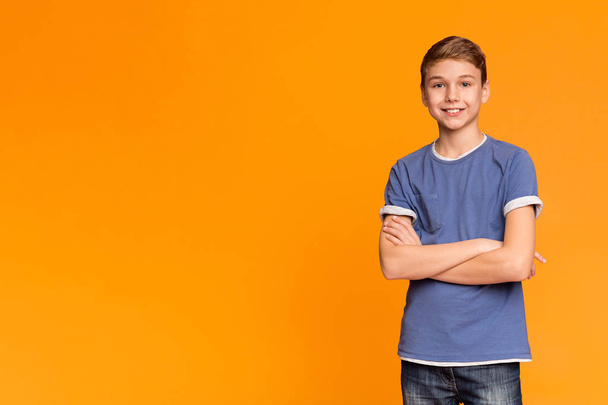 Cute teenage boy posing with folded hands and smiling - Φωτογραφία, εικόνα