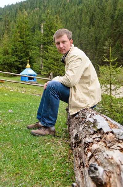 Mann sitzt auf einem alten Baumstamm - Foto, Bild