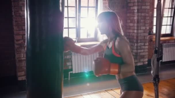 Bir kadın boksör kum torbasına vuruyor. Durur ve gülümseyerek - Video, Çekim