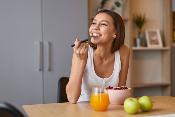 Happy woman eating healthy food during breakfast - Foto, Imagen