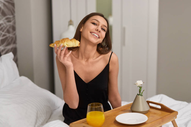 Cheerful woman having romantic breakfast in bed - Фото, изображение