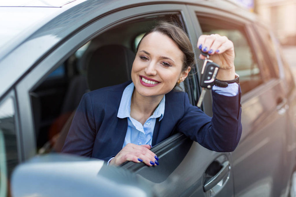 Young businesswoman sitting in car holding car keys - Foto, Imagen
