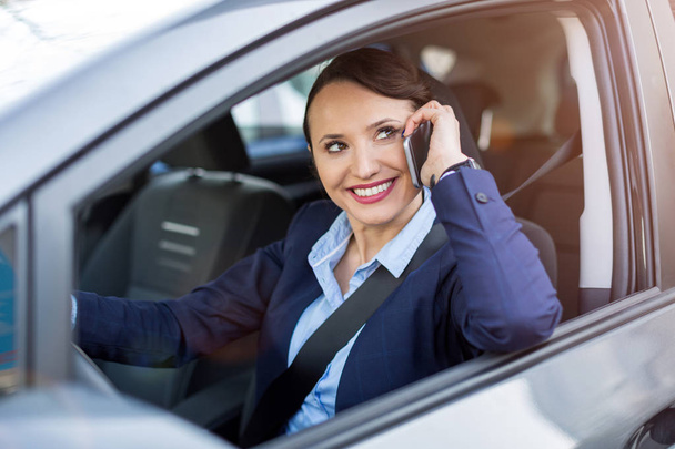 Woman using smartphone while driving a car - Foto, Bild