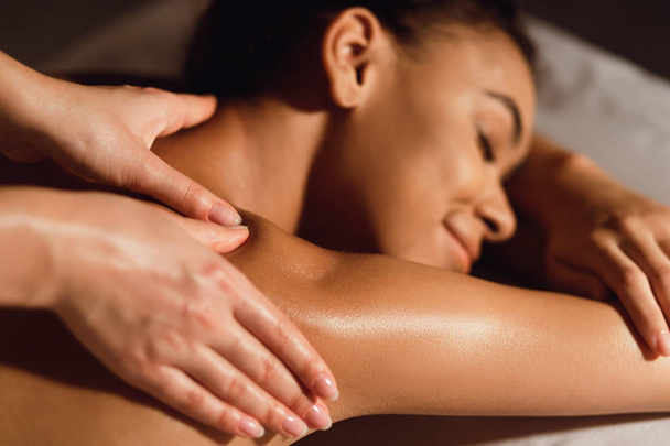 Afro-americana chica disfrutando de hombro masaje en spa
 - Foto, imagen