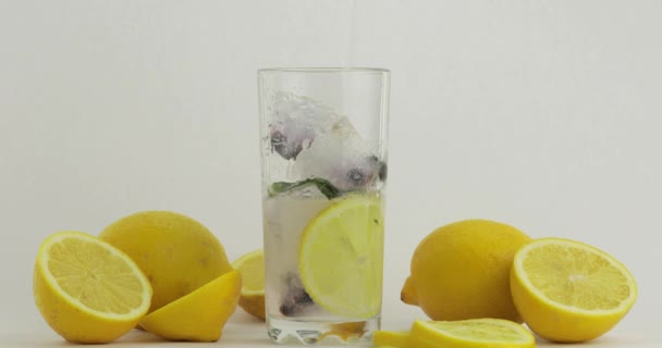 Ρίξτε ένα αναψυκτικό με κρύα σόδα. Λεμόνι και πάγος σε ένα ποτήρι ποτό. Δροσιστικό κοκτέιλ - Πλάνα, βίντεο