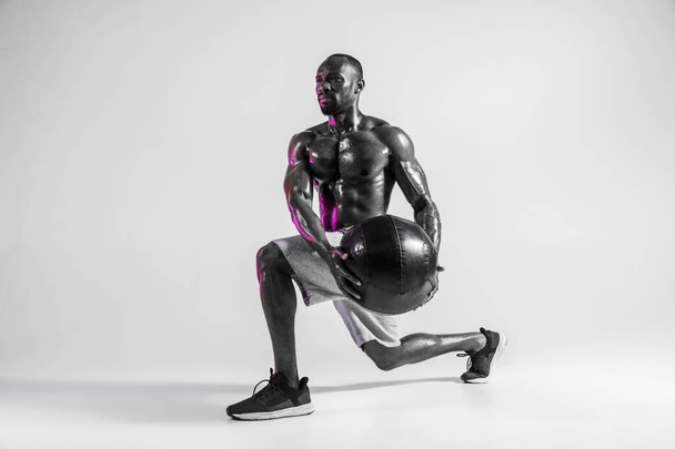 Young african-american bodybuilder training over grey background - Fotó, kép
