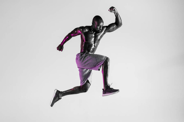 Young african-american bodybuilder training over grey background - 写真・画像
