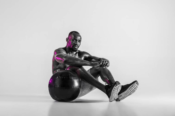 Young african-american bodybuilder training over grey background - Fotografie, Obrázek