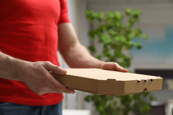 Courier with pizza box on blurred background, closeup - Фото, изображение